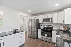 Kitchen featuring stainless steel appliances, tasteful backsplash, white cabinets, dark stone countertops, and recessed lighting