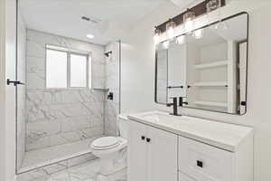Bathroom with light marble finish flooring, vanity, a stall shower, and recessed lighting