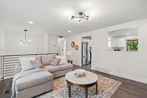 Living area featuring a chandelier, recessed lighting, and dark wood-type flooring