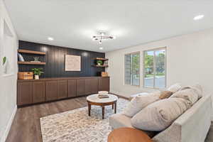 Living room with dark wood-style floors, wooden walls, and recessed lighting