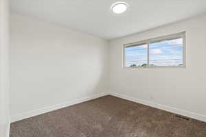 Unfurnished room featuring dark carpet and baseboards