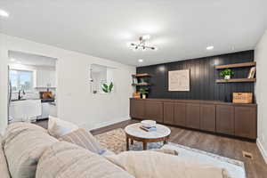 Living room with dark wood finished floors, recessed lighting, and wood walls
