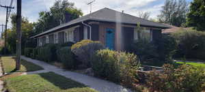 View of home's exterior featuring brick siding, a chimney, roof with shingles, a yard, and a garden