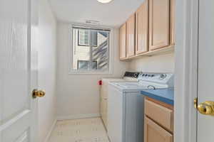 Washroom featuring separate washer and dryer and cabinet space