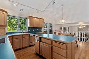 Kitchen featuring light wood-type flooring, plenty of natural light, pendant lighting, a center island, and high vaulted ceiling