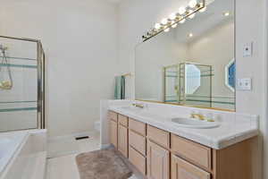 Bathroom featuring double vanity, a stall shower, tiled tub, and light tile patterned floors