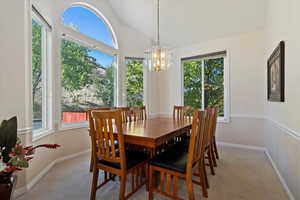Dining area with carpet, lofted ceiling, and a chandelier