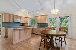 Kitchen featuring track lighting, light brown cabinetry, light countertops, white microwave, and light wood-style floors