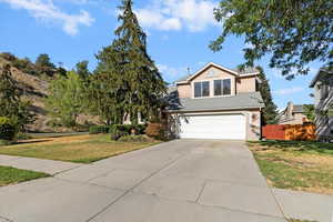 Traditional-style home featuring concrete driveway, an attached garage, stucco siding, and a shingled roof