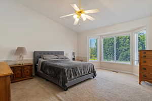 Bedroom featuring light carpet, lofted ceiling, and a ceiling fan
