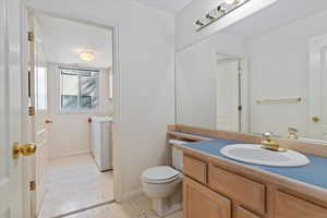Bathroom with vanity, washing machine and clothes dryer, and light floors