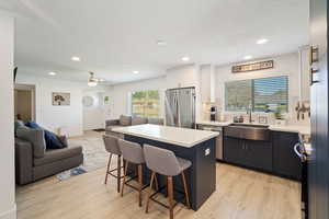 Kitchen with open floor plan, a kitchen bar, a kitchen island, light wood-type flooring, and recessed lighting