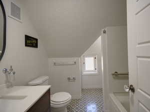Bathroom featuring a textured ceiling, vanity, and lofted ceiling