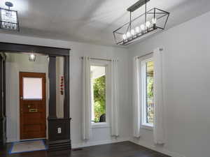 Foyer with dark wood-style floors, a textured ceiling, and ornate columns
