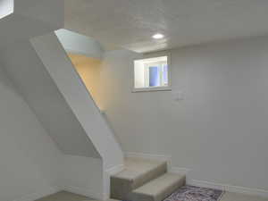 Staircase featuring a textured ceiling and carpet floors