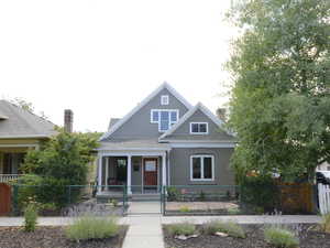 View of front of home with a gate, a porch, a fenced front yard, and roof with shingles