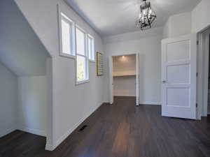 Hall with dark wood finished floors and a chandelier