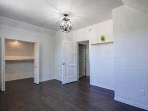 Unfurnished bedroom featuring dark wood-style flooring, a closet, a textured ceiling, and a chandelier