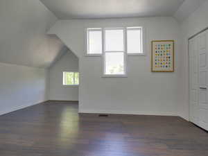 Bonus room featuring vaulted ceiling and dark wood-type flooring
