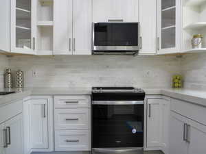 Kitchen featuring open shelves, glass insert cabinets, and appliances with stainless steel finishes