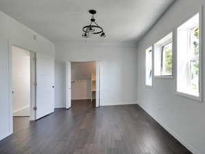 Unfurnished dining area with dark wood-style floors and a textured ceiling