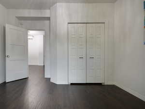 Unfurnished bedroom featuring dark wood-type flooring and a closet