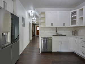 Kitchen with open shelves, appliances with stainless steel finishes, white cabinetry, dark wood finished floors, and decorative backsplash