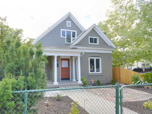 View of front facade with a fenced front yard, a gate, a porch, and a shingled roof