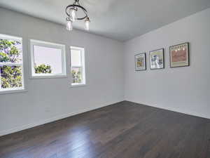 Spare room with dark wood-style floors and baseboards