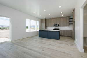 Kitchen with a center island with sink, modern cabinets, recessed lighting, open shelves, and stainless steel appliances