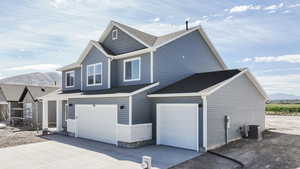 View of side of home featuring a mountain view, an attached garage, driveway, and a shingled roof
