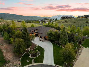 View of property's community with curved driveway, a patio, a mountain view, and a yard