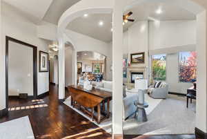 Living area with a ceiling fan, arched walkways, dark wood finished floors, recessed lighting, and a glass covered fireplace