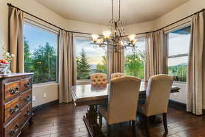 Dining room with healthy amount of natural light, dark wood-style floors, and a chandelier