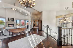 Dining space with a chandelier, high vaulted ceiling, a glass covered fireplace, dark wood-type flooring, and recessed lighting