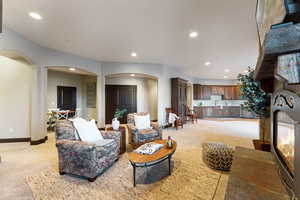 Living area featuring light colored carpet, recessed lighting, arched walkways, and a fireplace with flush hearth
