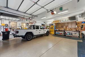 Garage with a workshop area, a heating unit, and a garage door opener