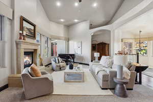 Living room with high vaulted ceiling, plenty of natural light, arched walkways, a chandelier, and a premium fireplace
