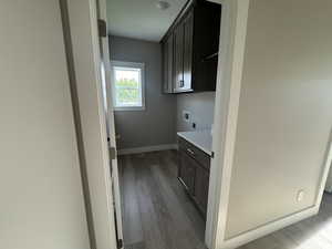 Laundry area with cabinet space, dark wood finished floors, hookup for a washing machine, and electric dryer hookup