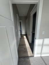 Hallway with baseboards and carpet