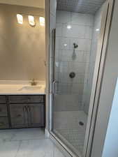 Bathroom with vanity, a shower stall, and light marble finish floors