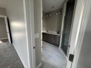 Bathroom with a shower stall, double vanity, and light marble finish floors