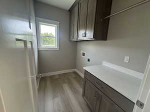 Laundry room featuring hookup for a washing machine, light wood-style flooring, cabinet space, and hookup for an electric dryer