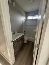 Bathroom featuring vanity, bathtub / shower combination, and dark wood finished floors
