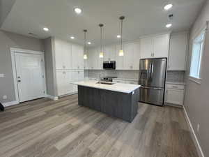 Kitchen with white cabinetry, appliances with stainless steel finishes, an island with sink, pendant lighting, and recessed lighting
