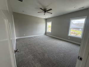 Unfurnished room featuring carpet, healthy amount of natural light, a textured ceiling, and a ceiling fan