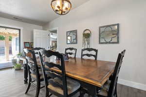 Dining space featuring a chandelier, light wood-type flooring, and lofted ceiling
