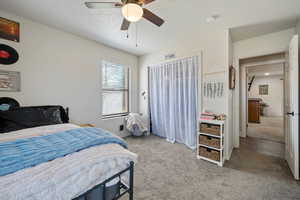 Bedroom with light carpet, a ceiling fan, and a textured ceiling