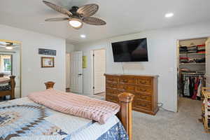 Bedroom featuring a spacious closet, light colored carpet, recessed lighting, ceiling fan, and attic access