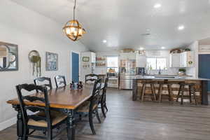 Dining area with dark wood-style floors, vaulted ceiling, and recessed lighting